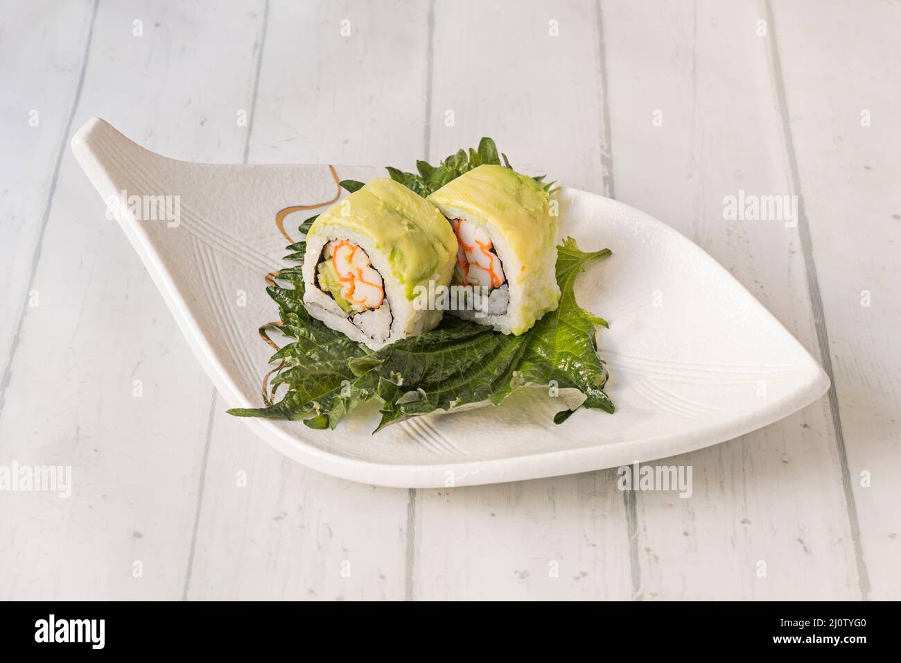 In Avocado gewickelte Brötchen, gefüllt mit Frischkäse und Schnittlauch und mehr auf einem Shiso-Blatt Stockfoto