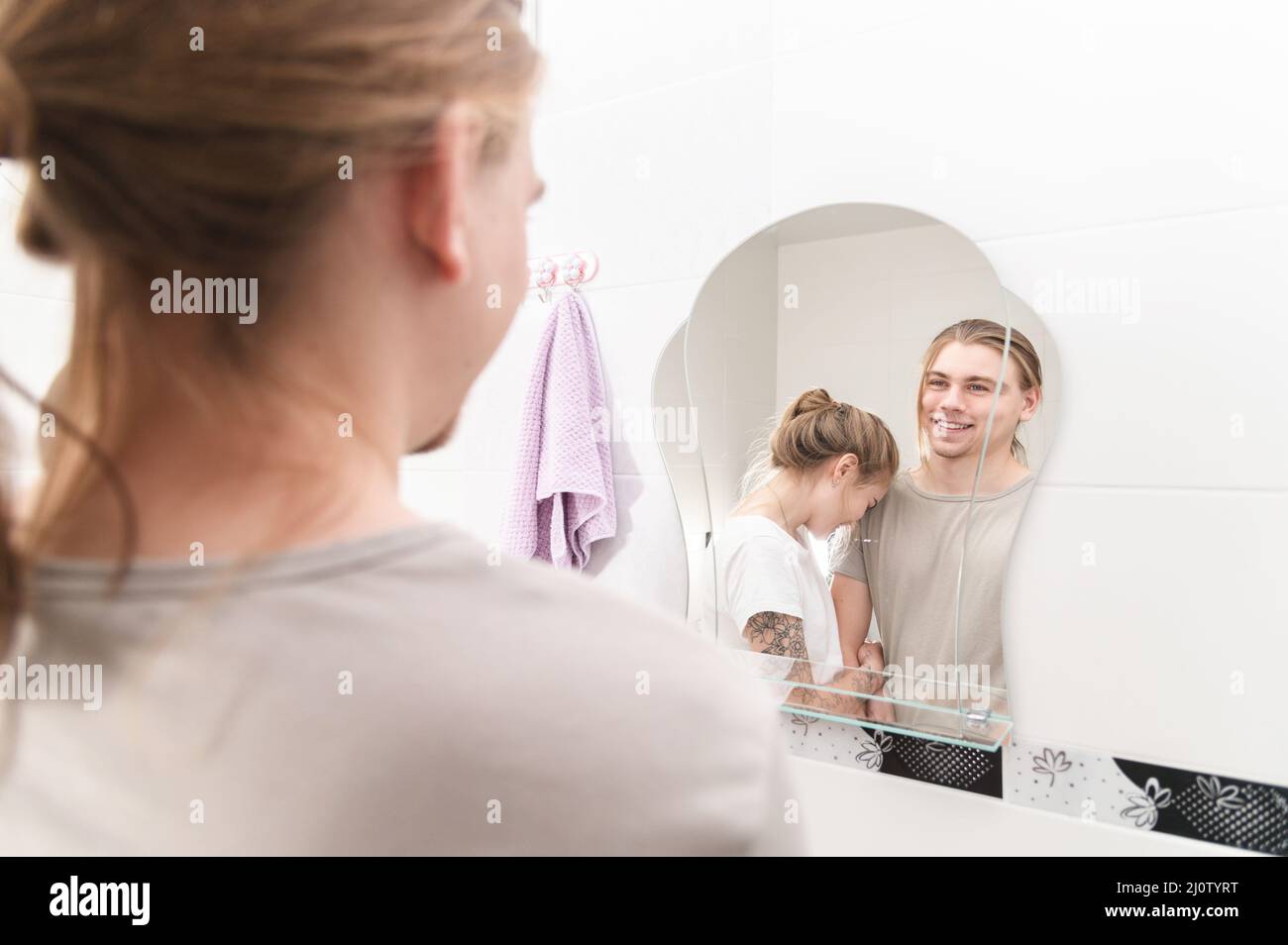 Das junge heterosexuelle Paar lacht morgens vor dem Badezimmerspiegel Stockfoto