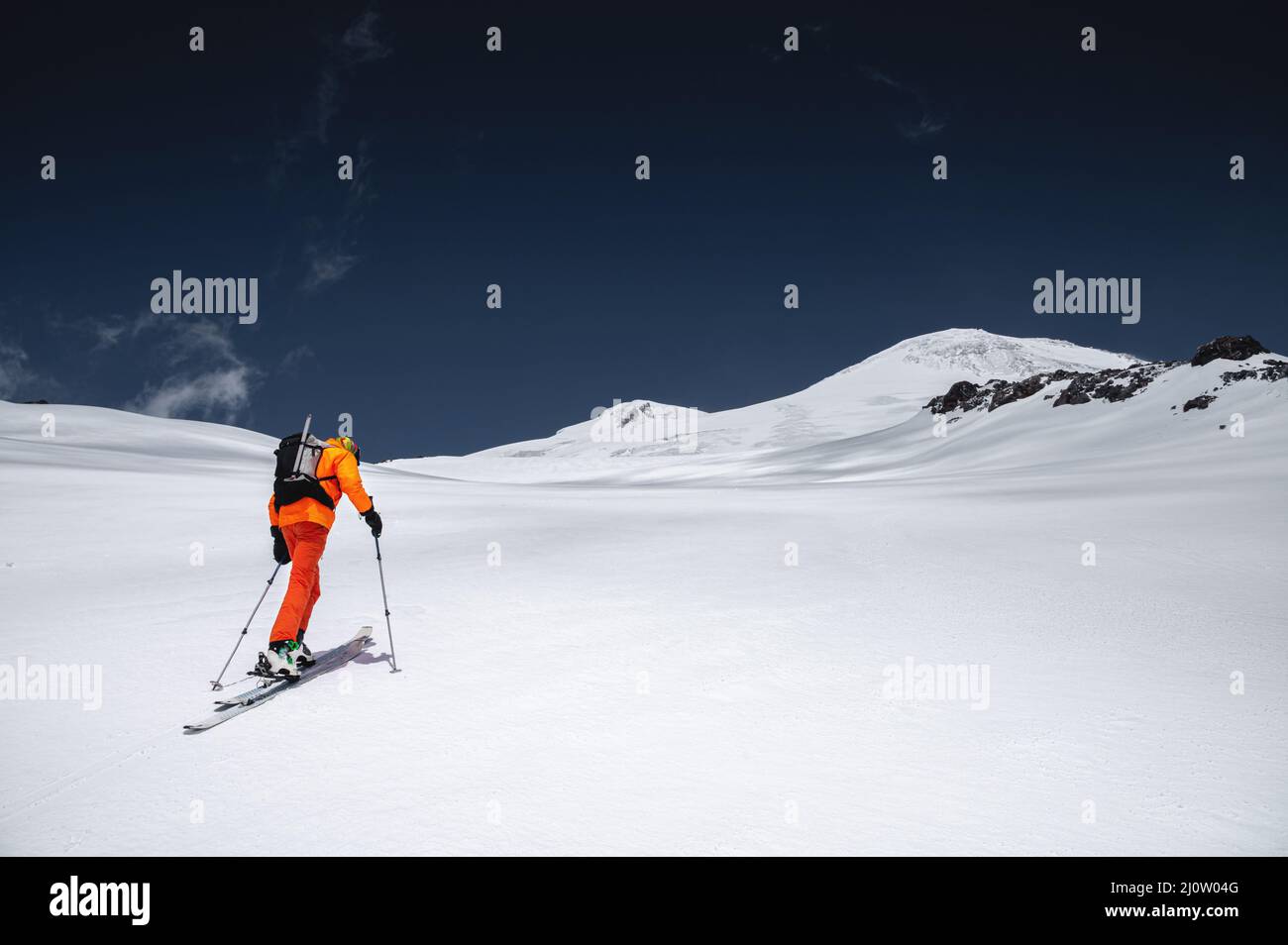 Ein Skifahrer in einem orangefarbenen Anzug Ski in einem Berg abseits der Piste Skifahren im nördlichen kaukasus des Mount Elbrus Stockfoto