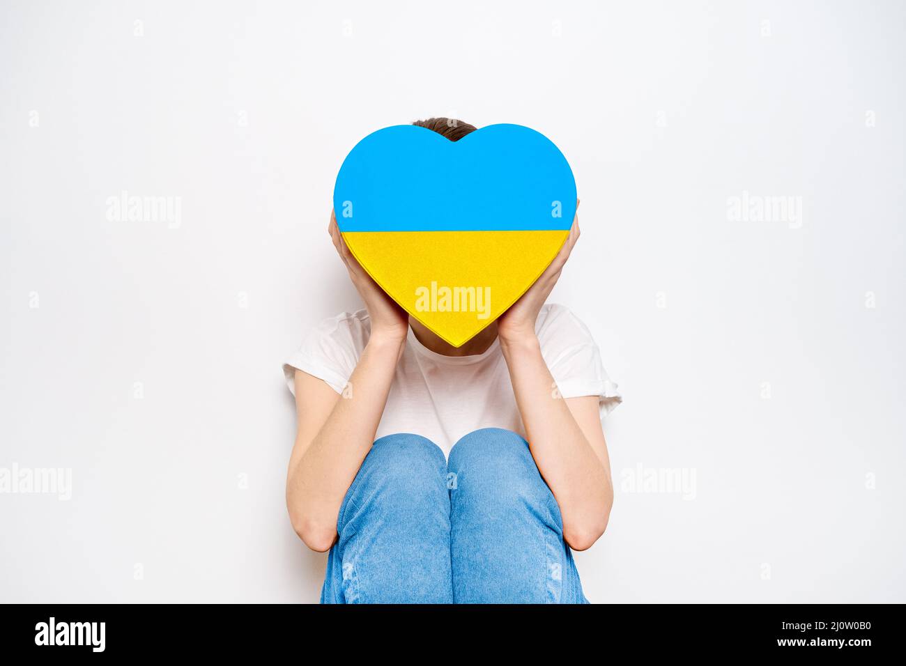 Frau mit einem großen gelben und blauen Kasten in Form eines Herzens. Trendiges Banner in der Farbe der ukrainischen Flagge Stockfoto