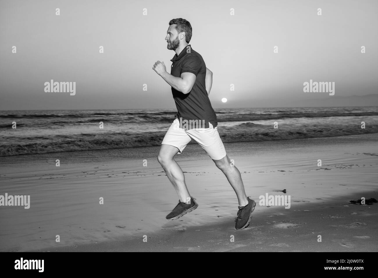 Athlet, Athlet, der am Sommerstrand bei Sonnenuntergang läuft Stockfoto