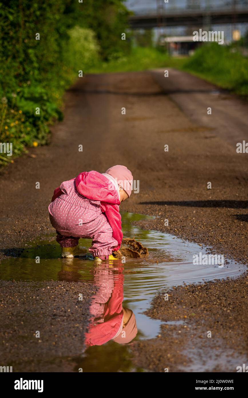 Ein kleines Kind spielt in einer Regenpfütze Stockfoto