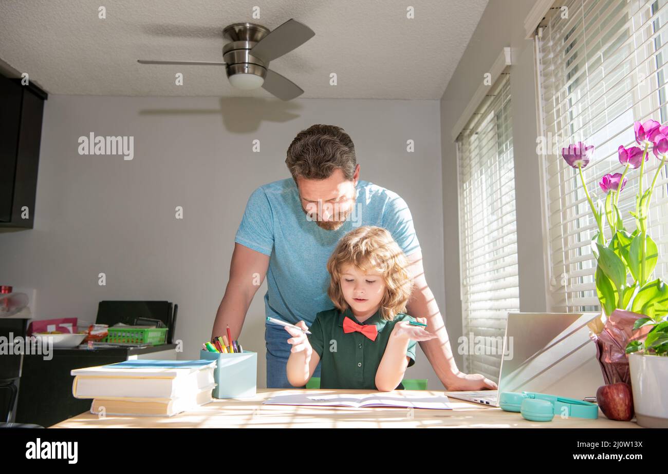 Bärtiger Vater schreibt Schulaufgaben mit seinem Jungen Sohn im Klassenzimmer, Schulunterricht Stockfoto
