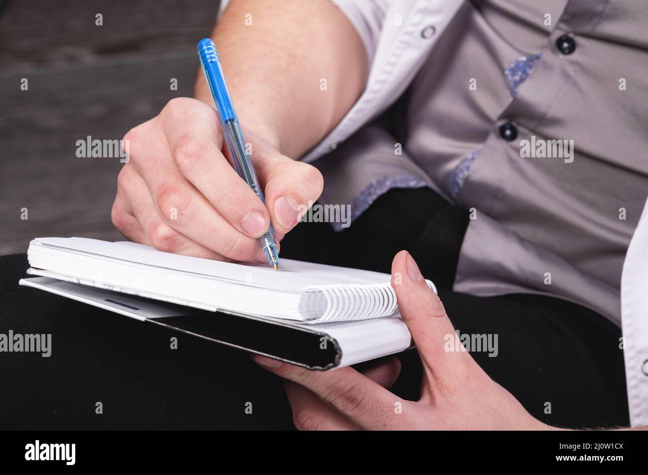 Die Männerhände eines Psychologen in einem weißen Gewand halten ein Notizbuch und einen Kugelschreiber mit einem Notizbuch bereit, um das aufzunehmen Stockfoto