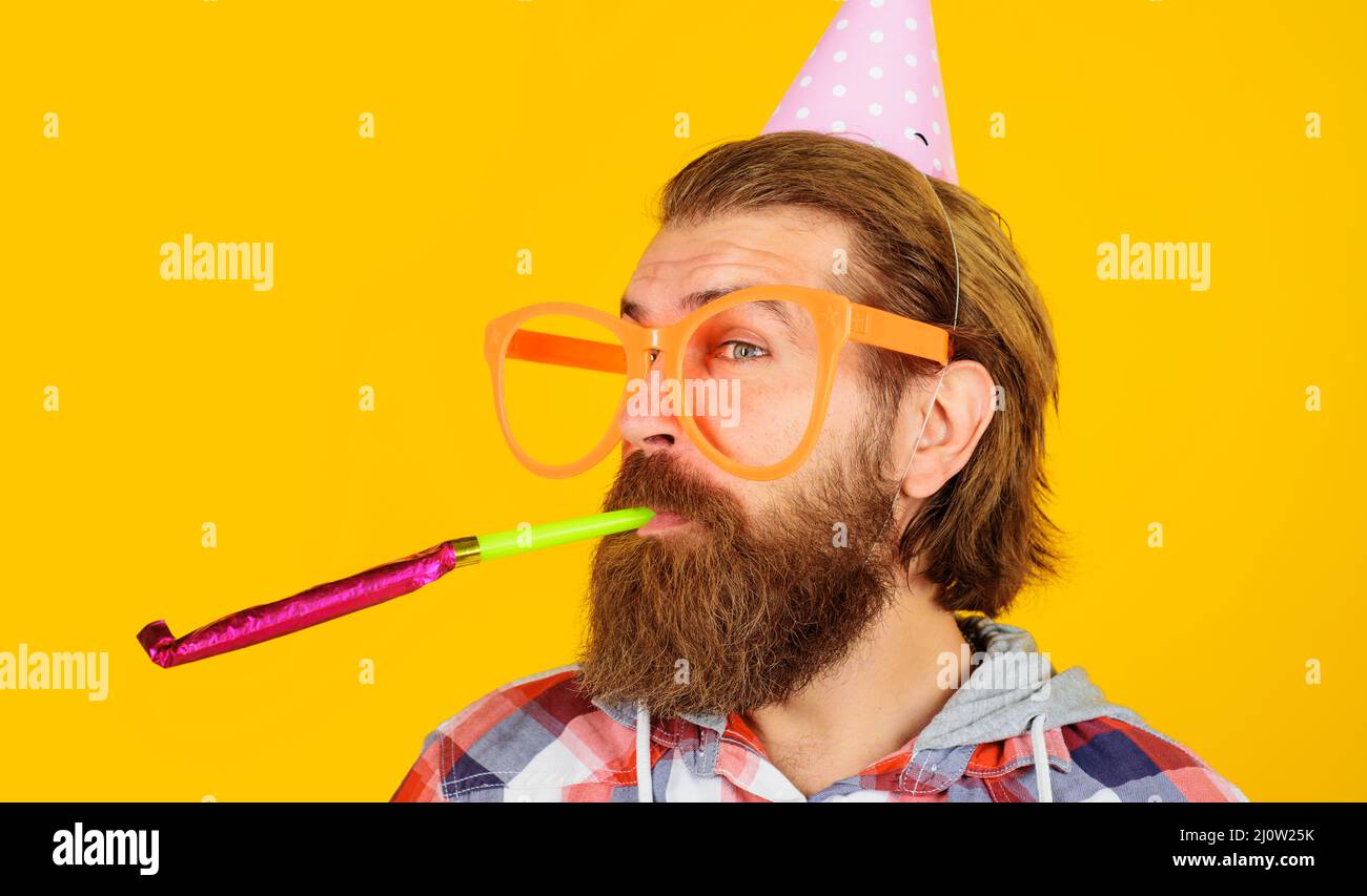 Partyzeit. Feiertage und Feiern. Bärtiger Mann mit Geburtstagskappe und großer Brille mit Noisemaker. Stockfoto