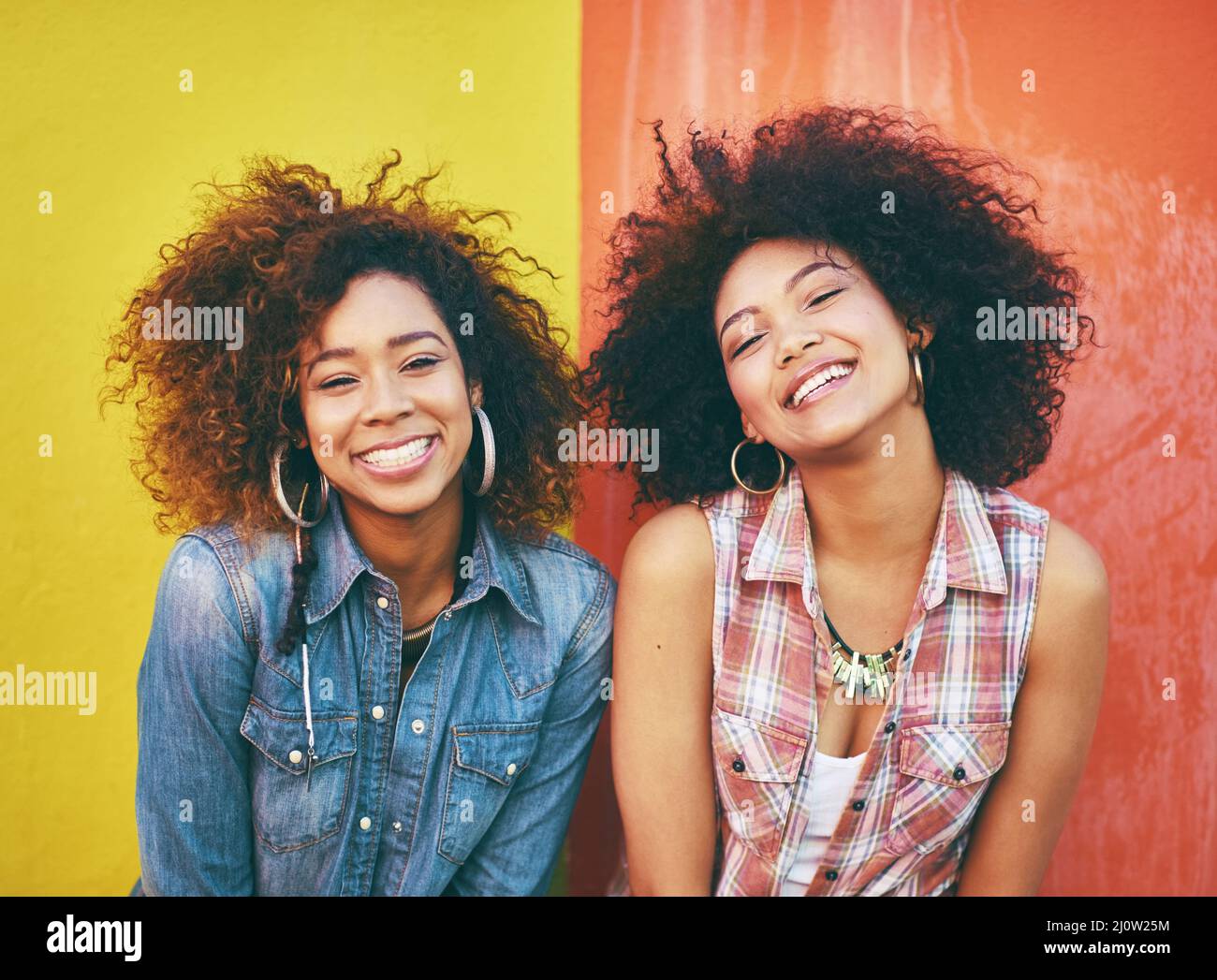 Modische Freunde. Porträt zweier junger Freunde, die vor einem farbenfrohen Hintergrund posieren. Stockfoto