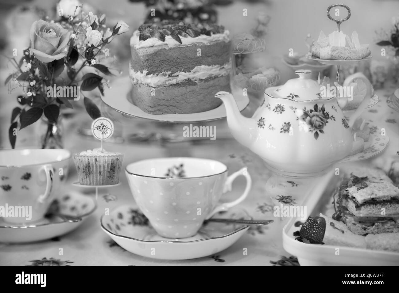 Ein eleganter Morgentee mit Teekannen im Blumenmuster und ein hausgemachter Biskuitkuchen mit Marmelade und Creme Stockfoto