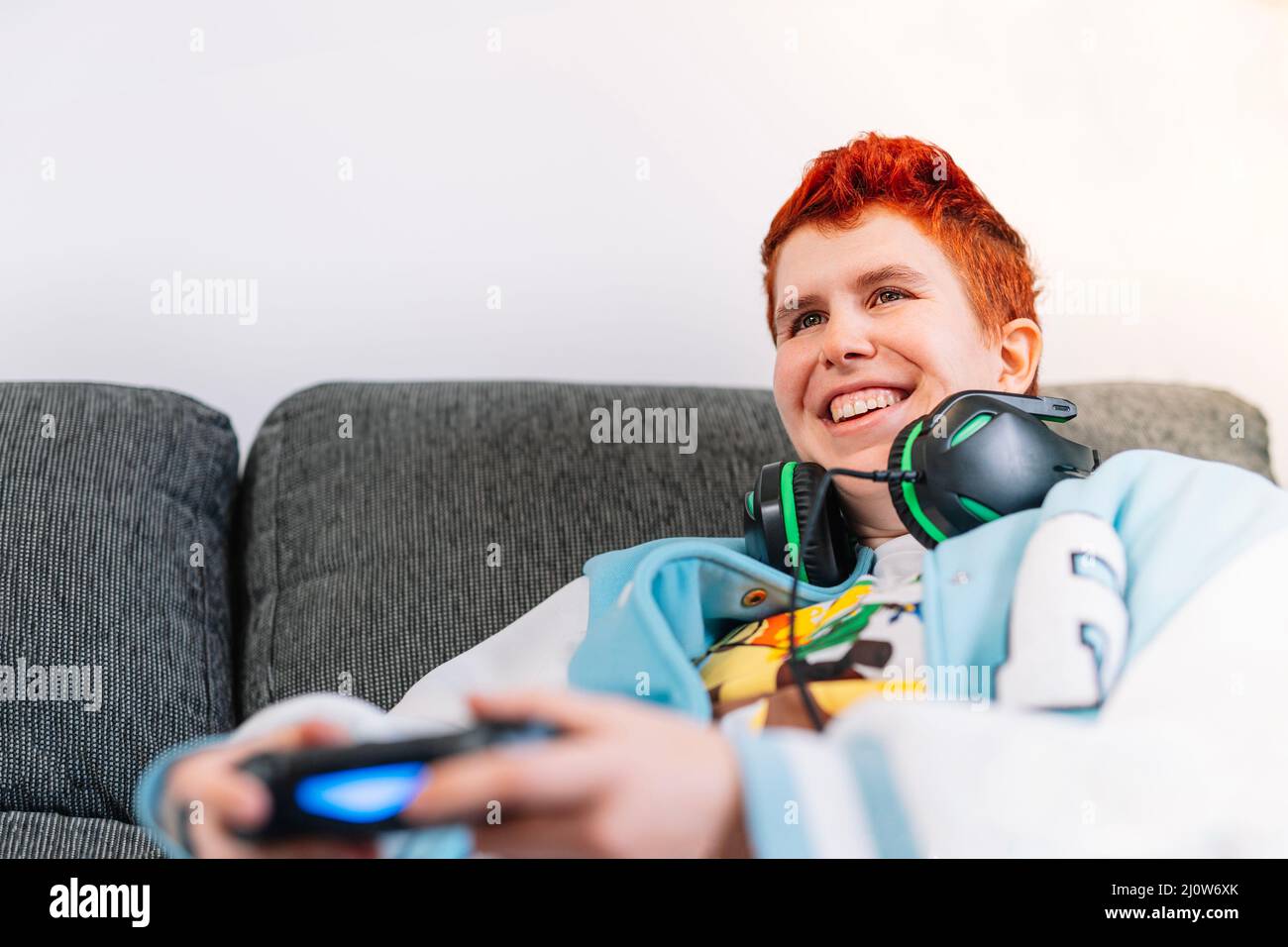 Nahaufnahme einer lächelnden, nicht-binären Person, die Videospiele im Wohnzimmer zu Hause spielt Stockfoto