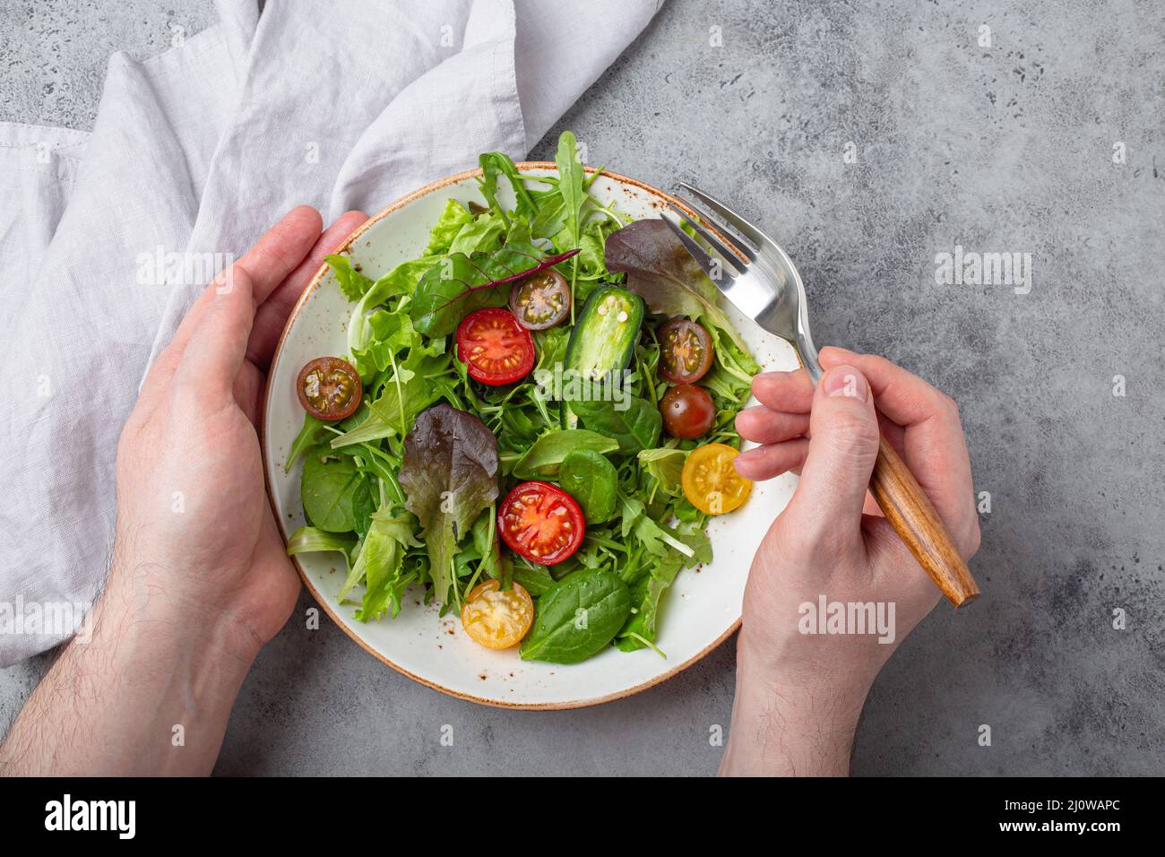 Mann, der vegetarisches Gemüse isst gesunder Salat mit roten und gelben Kirschtomaten Stockfoto