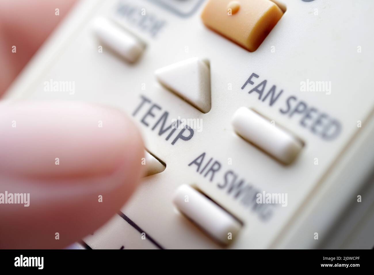 Nahaufnahme eines Fingers, der eine Taste auf der Fernbedienung der Klimaanlage drückt Stockfoto