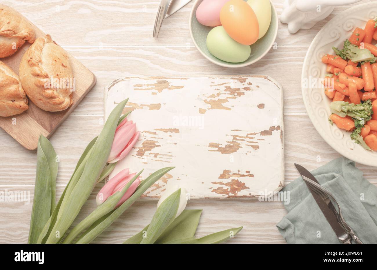 Weiße leere Holzschneidebrett und Ostern Essen auf Küchentisch Stockfoto