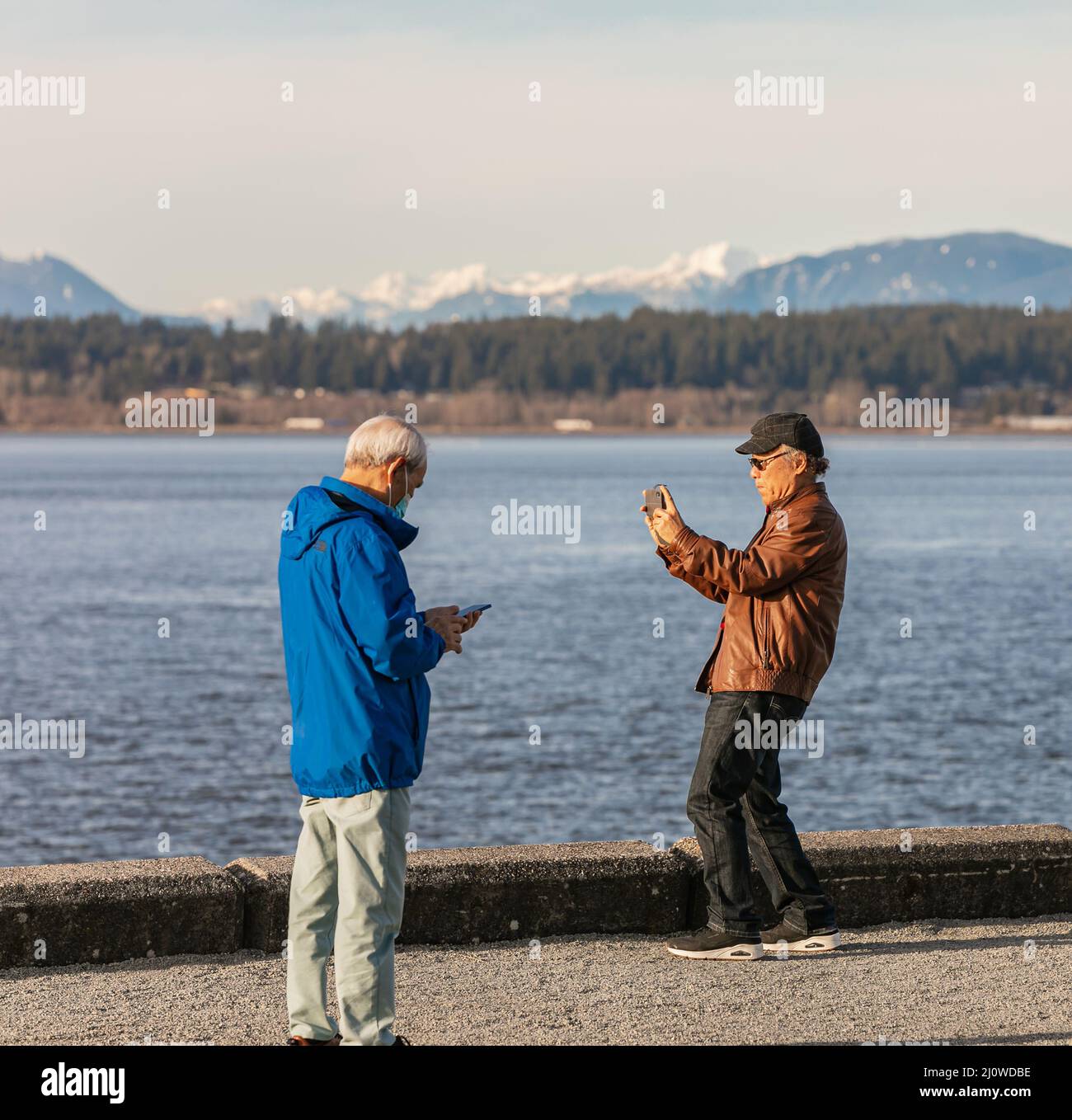 Asiatischer älterer Mann mit einem Smartphone. Ein Mann, der mit seinem Handy im Park Fotos machte. Stockfoto