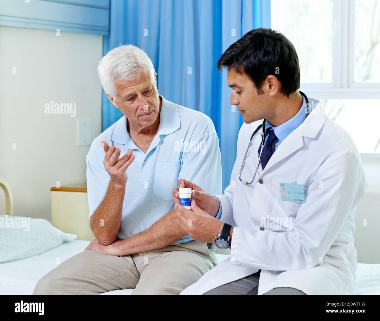 Nehmen Sie sich einfach einen pro Tag. Aufnahme eines hübschen jungen Arztes, der einem älteren Patienten Medikamente erklärt. Stockfoto