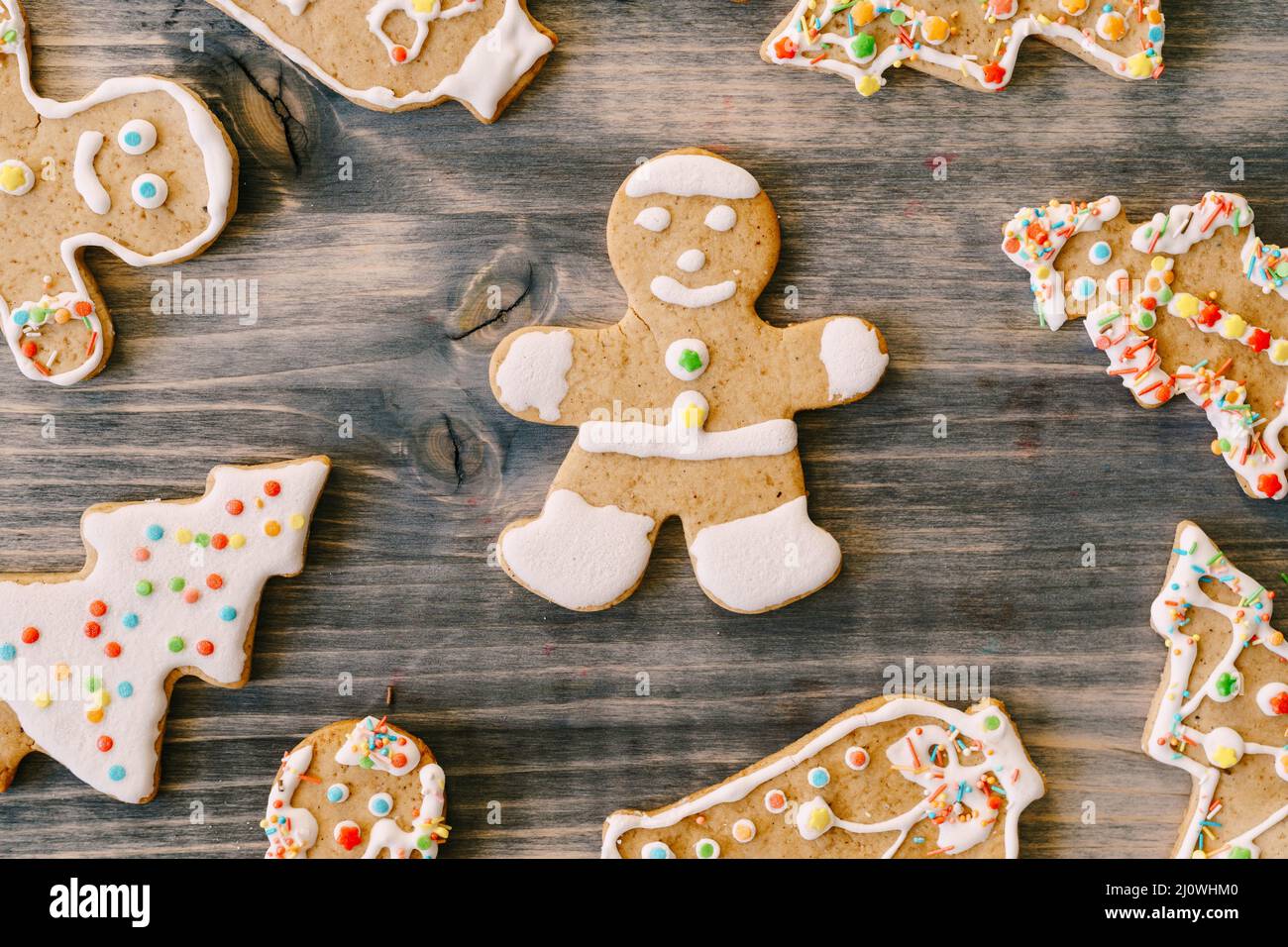 Nahaufnahme Lebkuchenmann auf einem Holztisch, umgeben von Weihnachtskeksen in verschiedenen Formen. Stockfoto