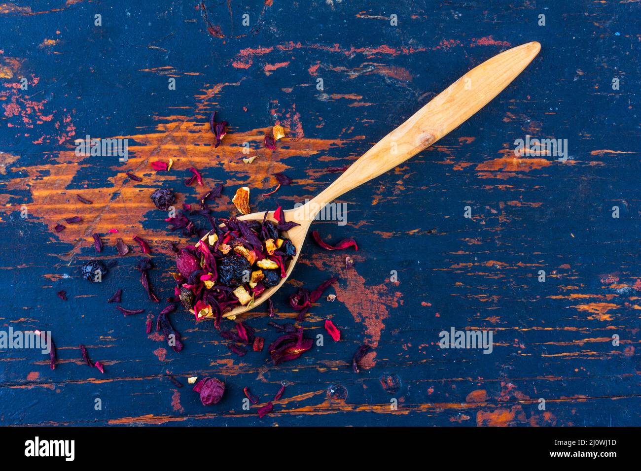 Holzlöffel mit getrocknetem Blumentee auf einem alten schwarzen Holzhintergrund Draufsicht Stockfoto