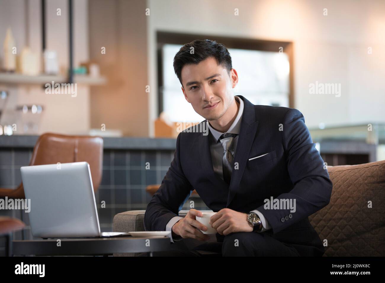 Der erfolgreiche chinesische Geschäftsmann arbeitet mit dem Computer in Cafés Stockfoto