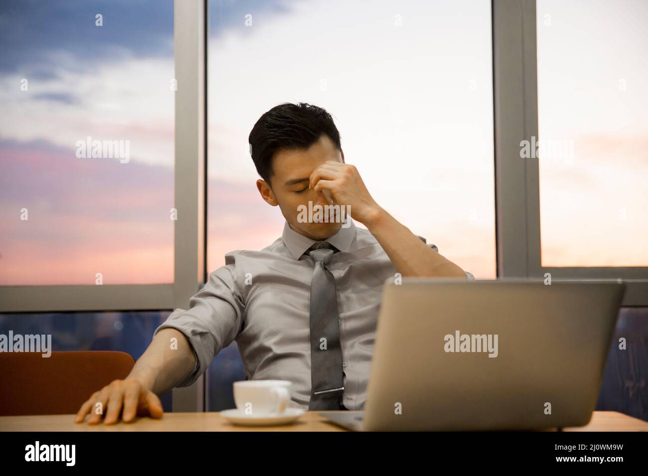 Müde chinesische junge Geschäftsmann arbeitet im Büro Stockfoto