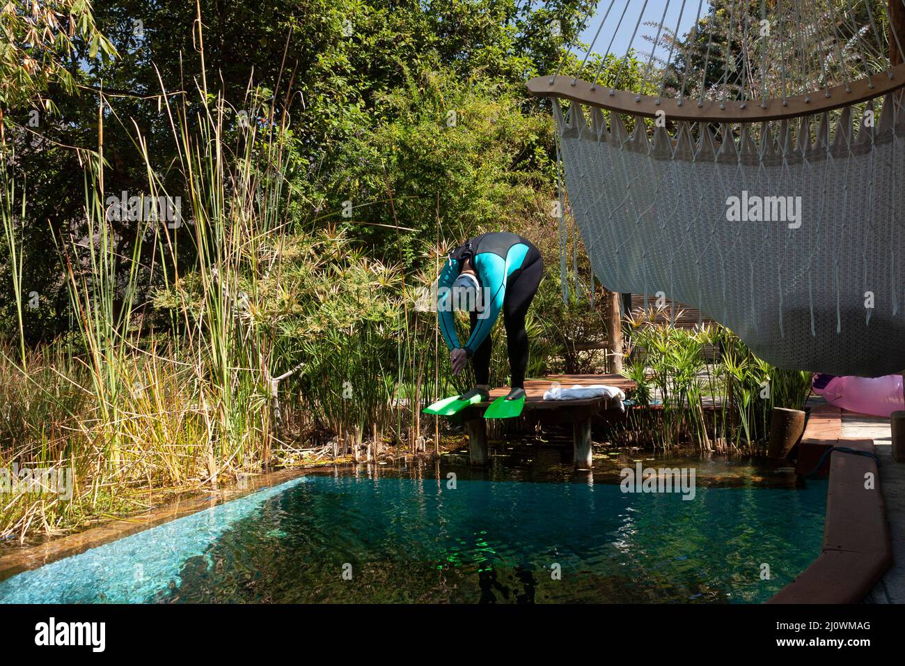 Konzentrierte Frau in der Haltung zum Tauchen im Wasser trägt Thermal-Anzug Mütze und Googles für körperliches Training und Sport im Schwimmen in Mexiko Stockfoto