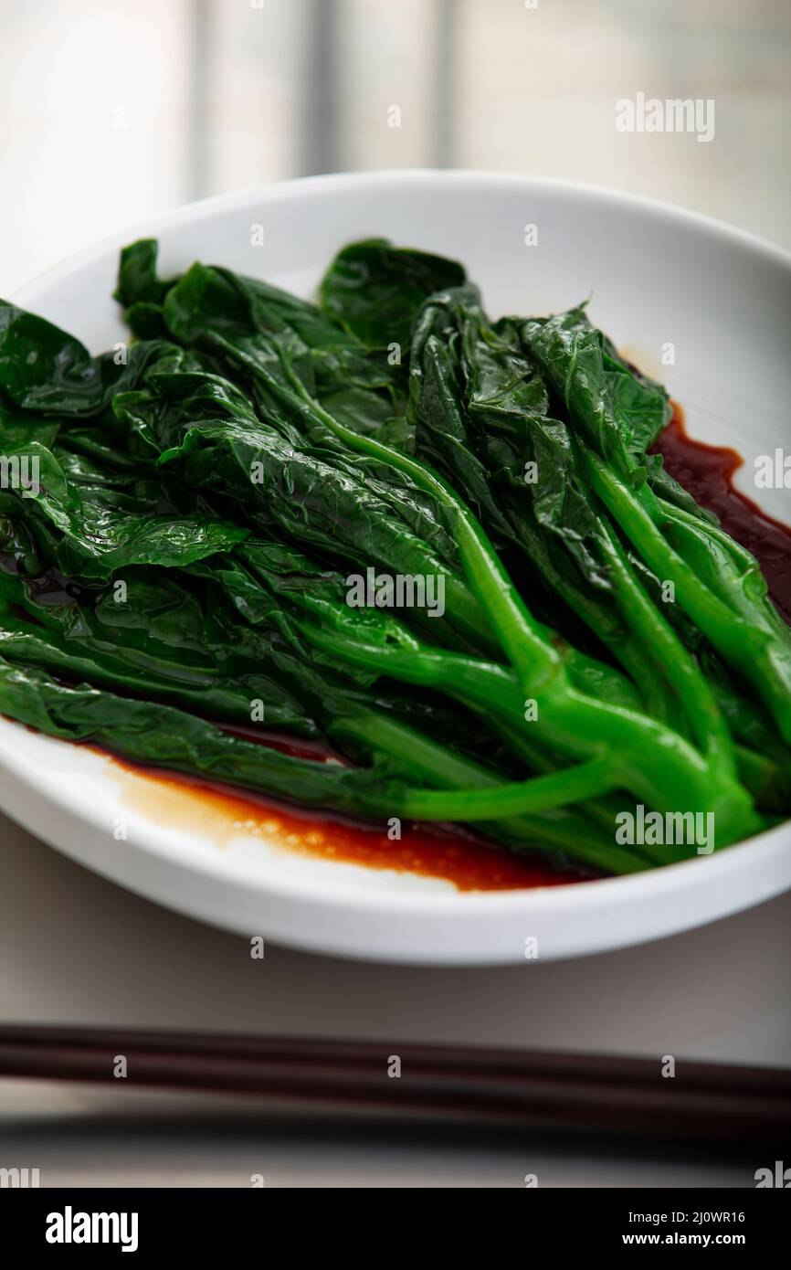 Kantonesische Küche, Nahaufnahme von gekochtem chinesischen Grünkohl mit Sojasauce Stockfoto