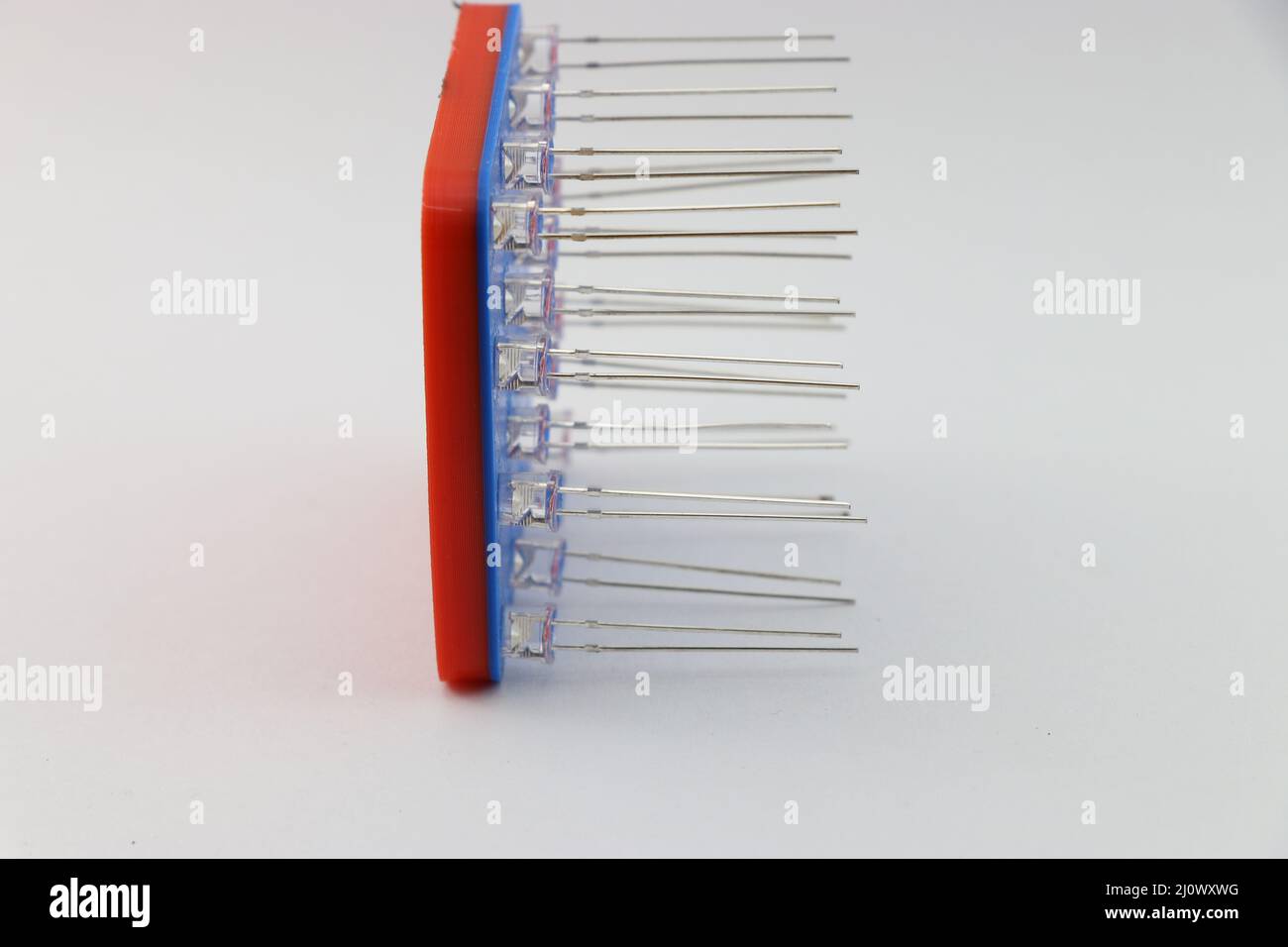 Seitenansicht von 3D gedruckten LED-Jig mit Leuchtdioden, die an den Schlitzen angebracht sind, mit der Ansicht der LED-Pins, die auf weißem Hintergrund angeordnet sind Stockfoto