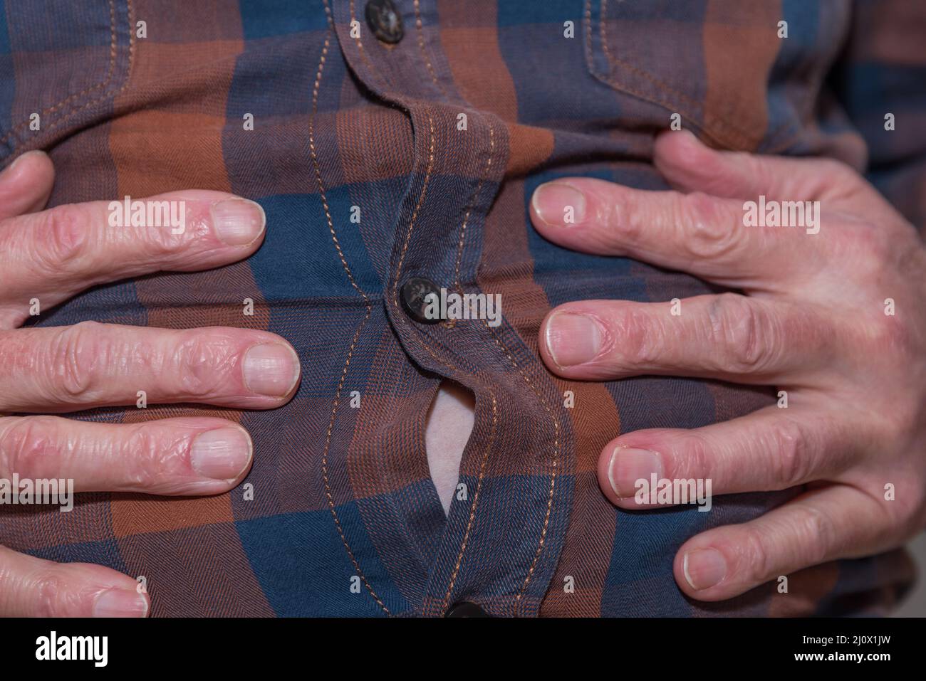 Übergewichtiger Mann hält die Hände auf dem Bauch - Nahaufnahme Stockfoto