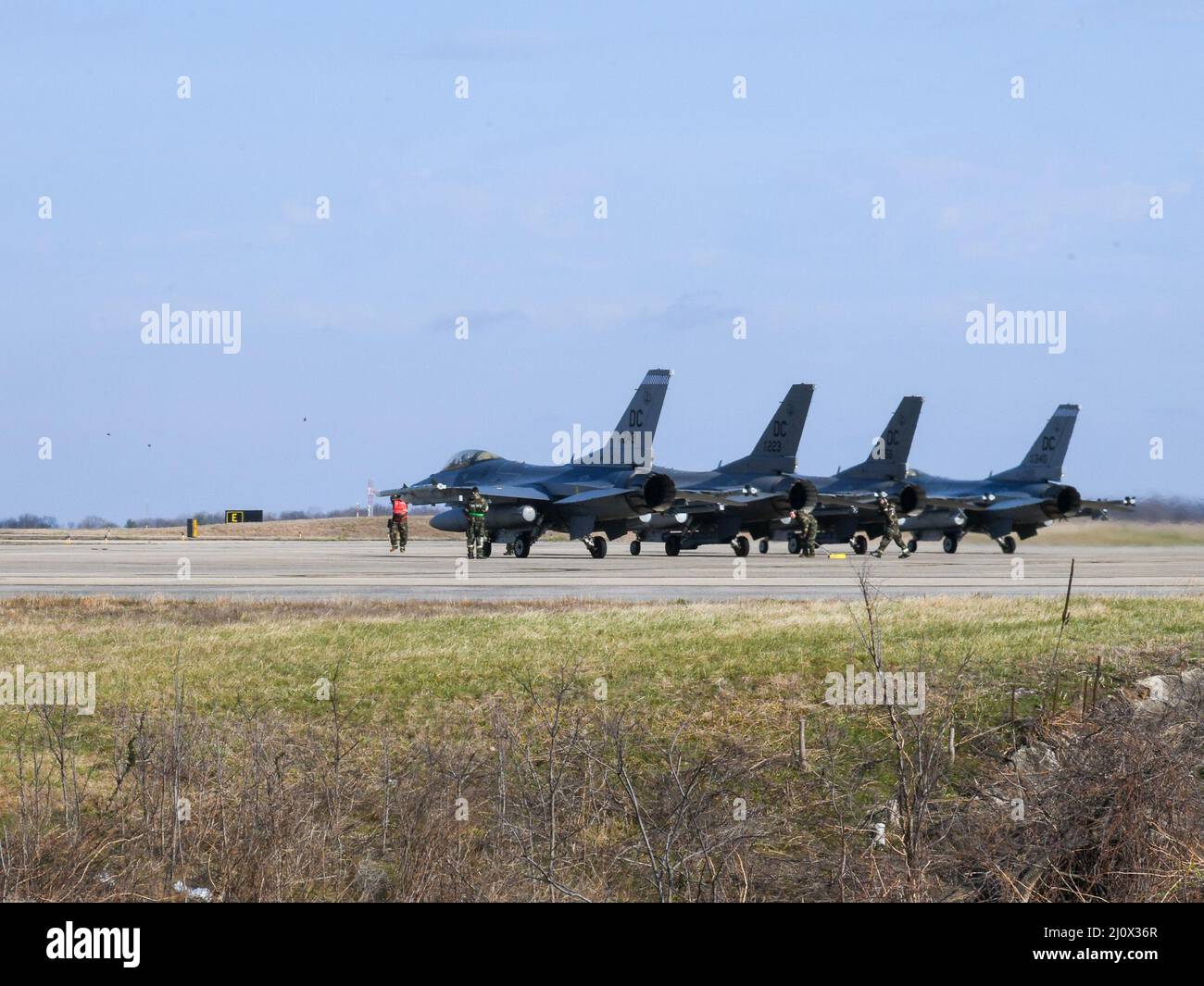 F-16-Kämpfer, die von der 121. Fighter Squadron, 113. Wing, District of Columbia Air National Guard, betrieben werden, werden vor dem Start in der Nähe der Start- und Landebahn im Rahmen einer Übung zur Überlebensfähigkeit und zum Einsatz der Einsatzbereitschaft auf der Joint Base Andrews, Maryland, 19.. März 2022, eingesetzt. Die Übung simulierte eine umkämpfte Umgebung mit chemischen Waffen, um die Besatzung und anderes Personal in Schutzanzügen und Masken für ihre Rolle zu Schulen. (USA Foto der Air National Guard von Tech. Sgt. Andrew Enriquez) Stockfoto