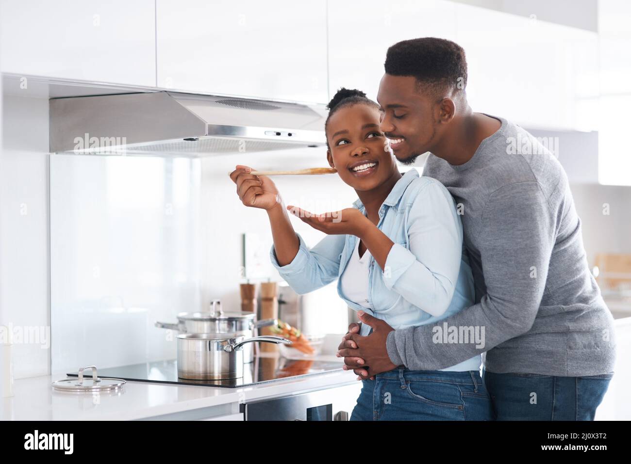 Sie wissen bereits, dass alles, was Sie machen, köstlich ist. Aufnahme eines Mannes, der seine Frau von hinten umarmt, während er mit dem Kochen beschäftigt ist. Stockfoto