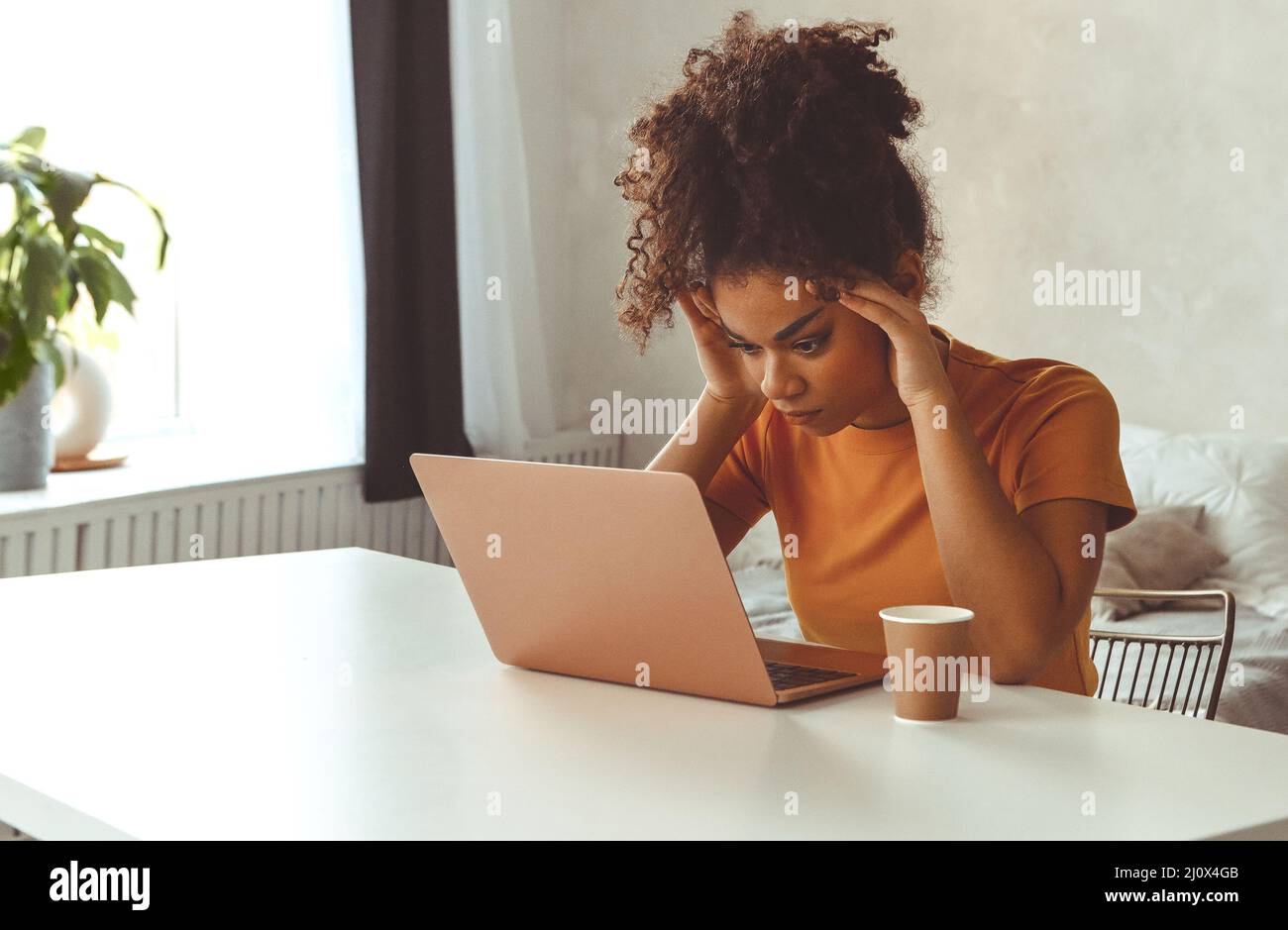 Frustrierte junge afrikanisch abstammende Frau zu Hause vor dem Laptop und erhielt E-Mails mit schlechten Nachrichten Stockfoto