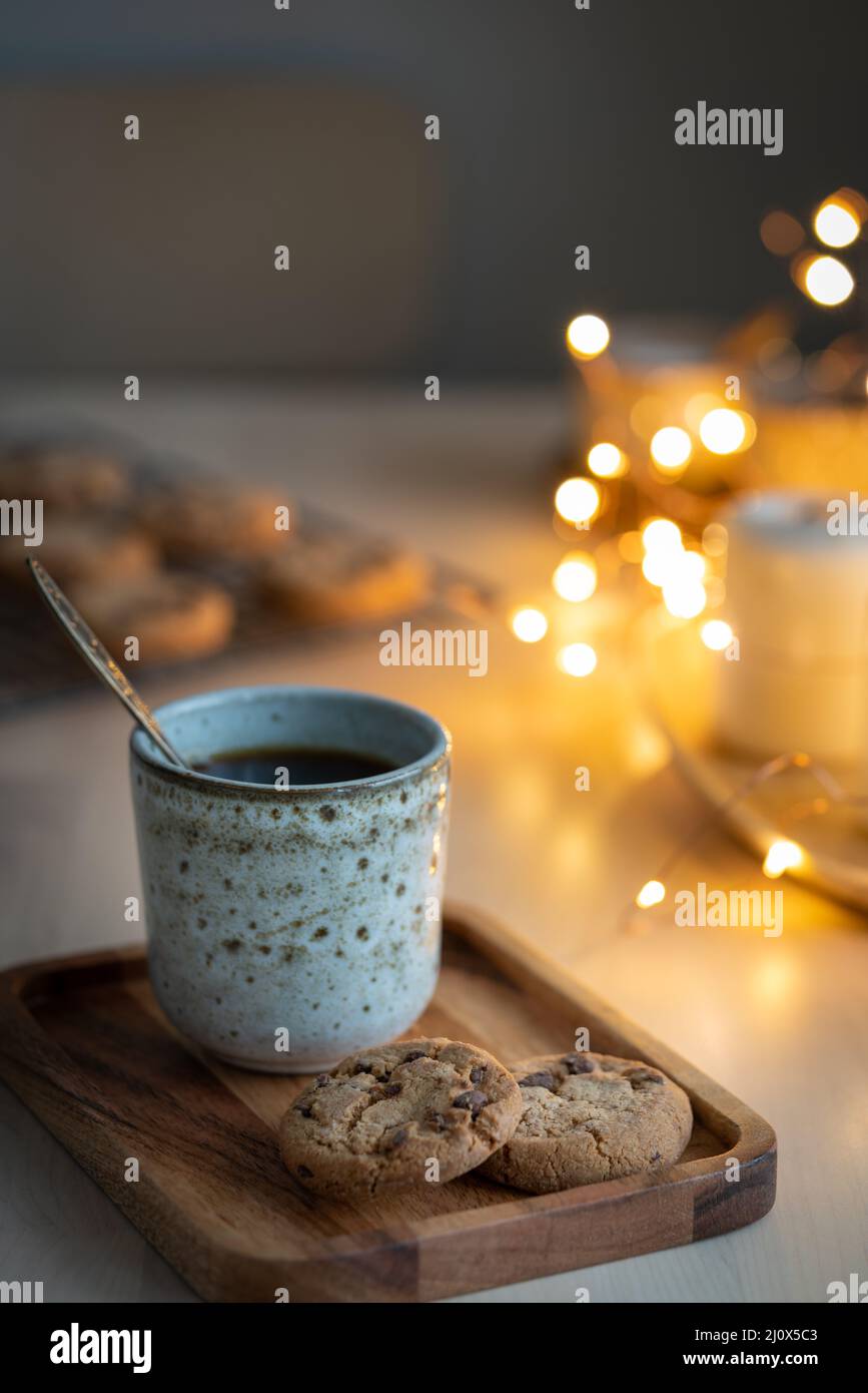 Gemütlicher Abend, Becher mit Getränk, Weihnachtsdekoration, Kerzen und Lichter Girlanden. Stockfoto