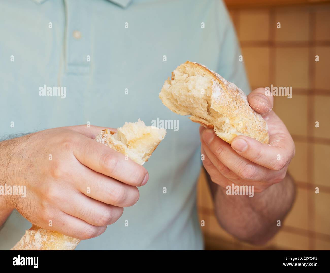Mann bricht aus Hunk von frisch gebackenen hausgemachten knusprigen Brot Baguette. Köstlich Stockfoto