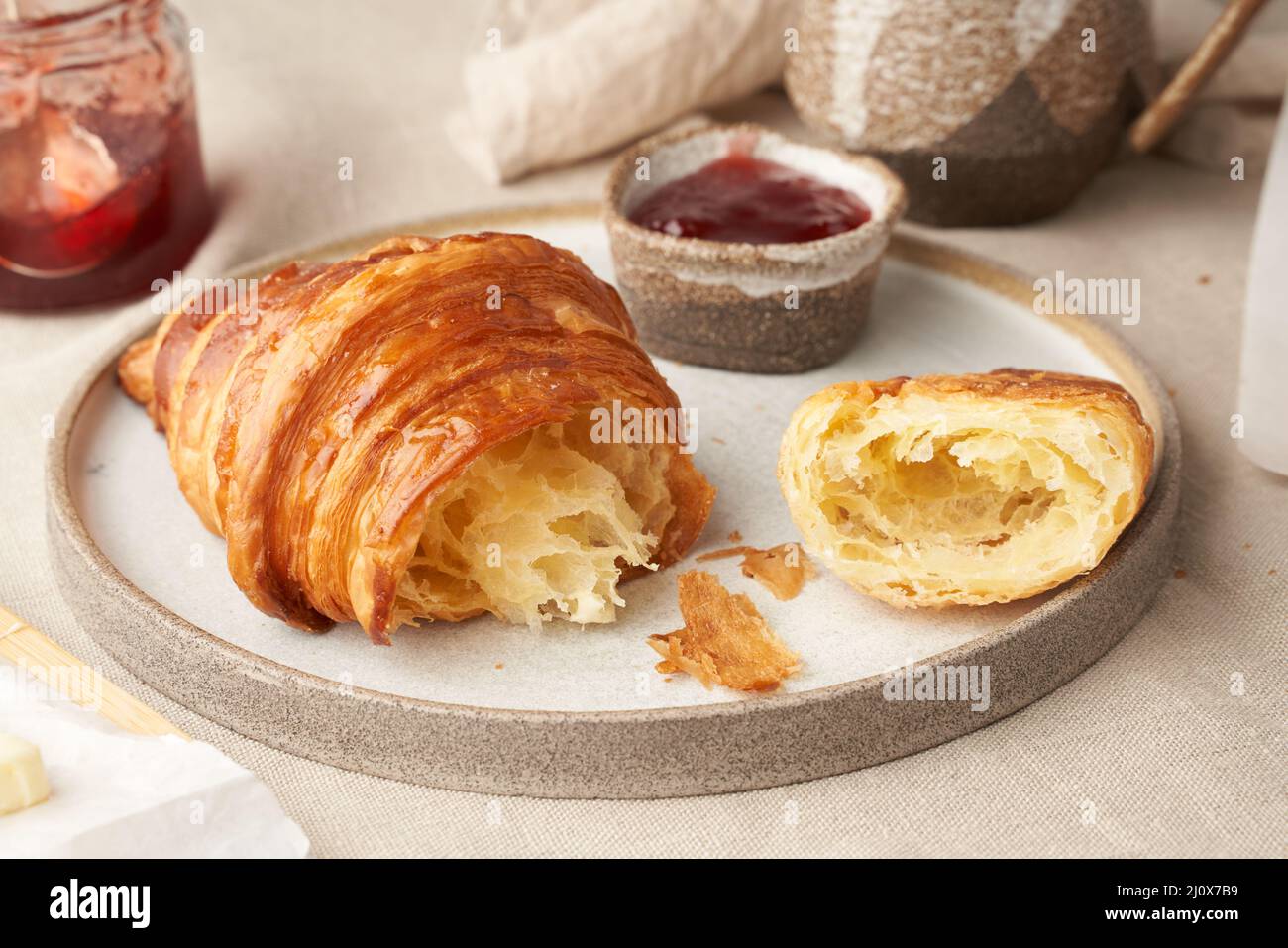 Ein köstliches Croissants auf dem Teller und ein warmes Getränk im Becher. Morgens französisches Frühstück Stockfoto