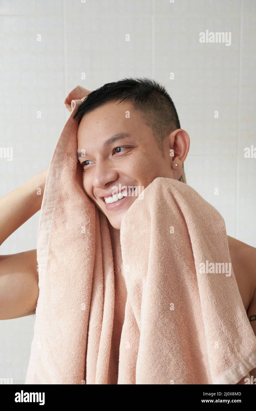 Lächelnder junger Mann, der nach der Dusche am Morgen mit einem weichen Handtuch abwischte Stockfoto