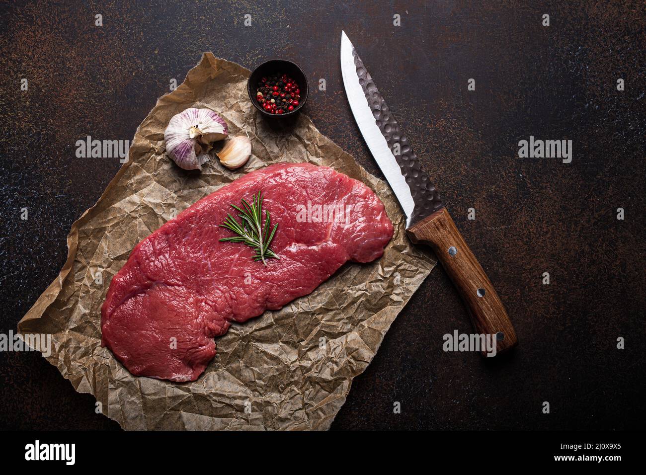 Rindermager Roh-Filetsteak auf Backpapier mit Rosmarin, Knoblauch und Gewürzen Stockfoto