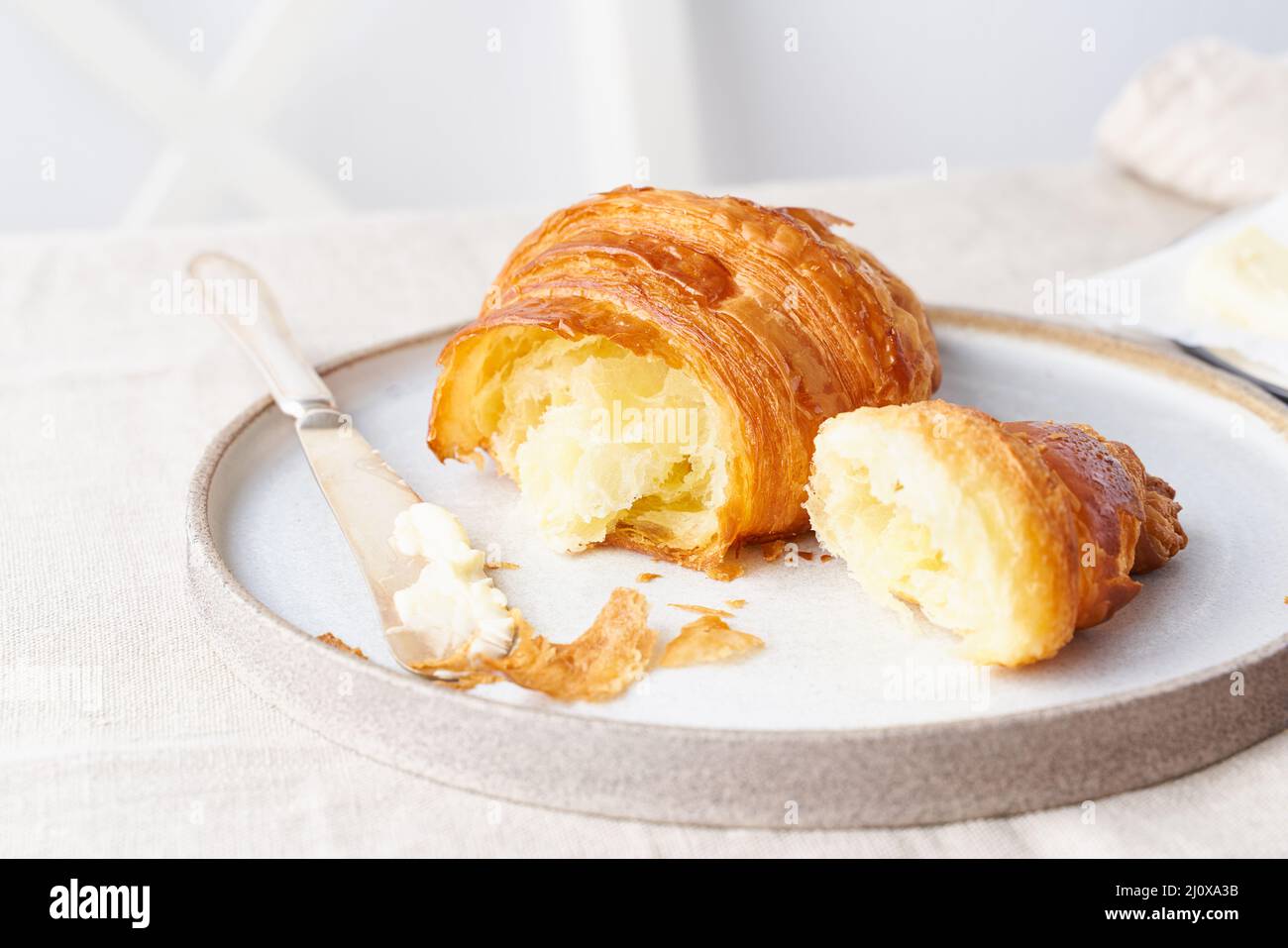 Kaffee mit Croissant. Heller sonniger Morgen, gemütliches Frühstück mit frischem Gebäck, seitlichem Blick Stockfoto