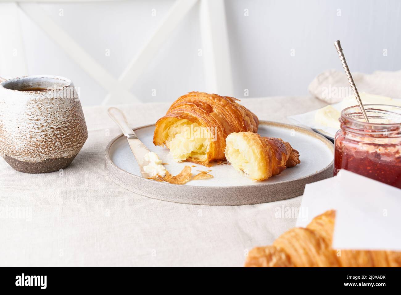 Kaffee mit Croissant. Heller sonniger Morgen, gemütliches Frühstück mit frischem Gebäck, seitlichem Blick Stockfoto