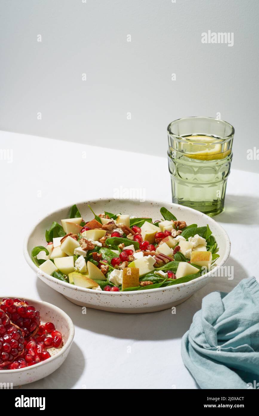 Obstsalat mit Nüssen, ausgewogene Lebensmittel. Hartes Licht, Schatten. Spinat mit Äpfeln, Pekannüsse, vertikal Stockfoto