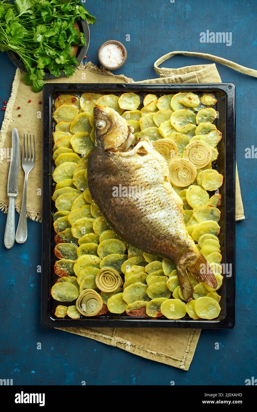 Gebackene Karpfen, ganze Fische aus dem Ofen mit Kartoffelscheiben auf ...