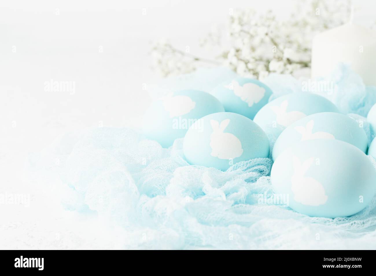 Ostern. Urlaub. Hellweißer Hintergrund, sanfte Pastellfarben. Blaue Eier mit Bild von Kaninchen Stockfoto