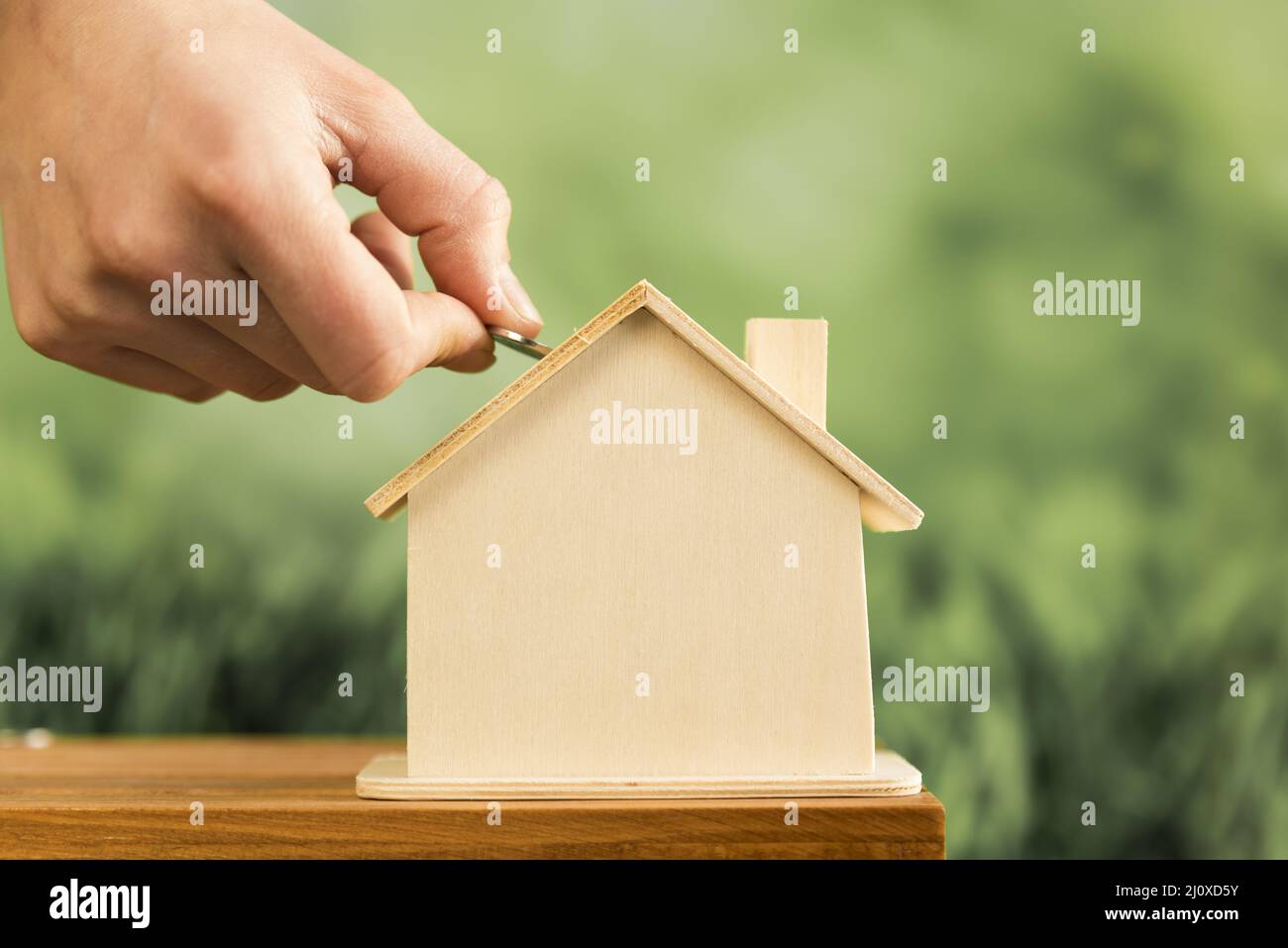 Close up Hand einfügen Münze Holzhaus Holztisch. Hochwertiges, schönes Fotokonzept Stockfoto