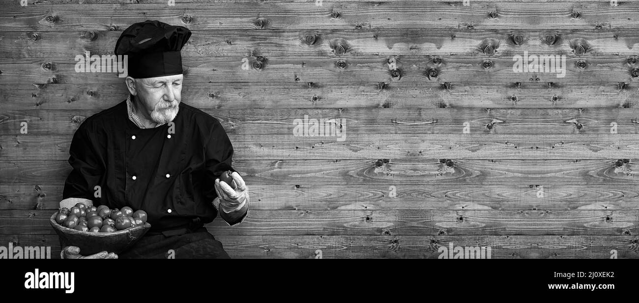 Landwirt in Uniform mit frischem Gemüse auf einem Holzboden Stockfoto