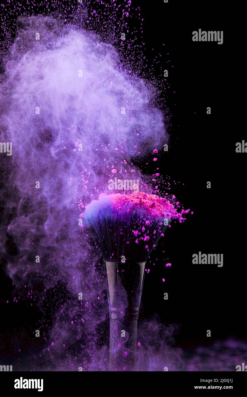 Lebendige Burst Make-up Pulver mit Pinsel dunklen Hintergrund. Hochwertiges, schönes Fotokonzept Stockfoto