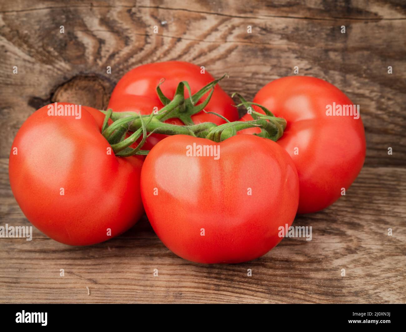 Zweig der reifen Tomaten auf rustikal verwitterten Holztisch Stockfoto