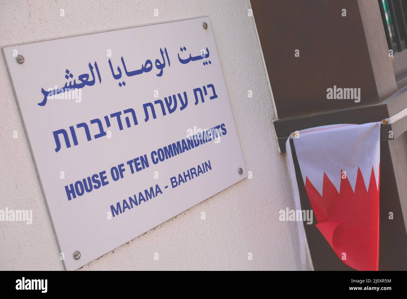 Sign in Arabisch, Hebräisch und Englisch, und eine Bahraini-Flagge vor der Synagoge des Hauses der zehn Gebote, Souk-Bereich, Manama, Königreich Bahrain Stockfoto