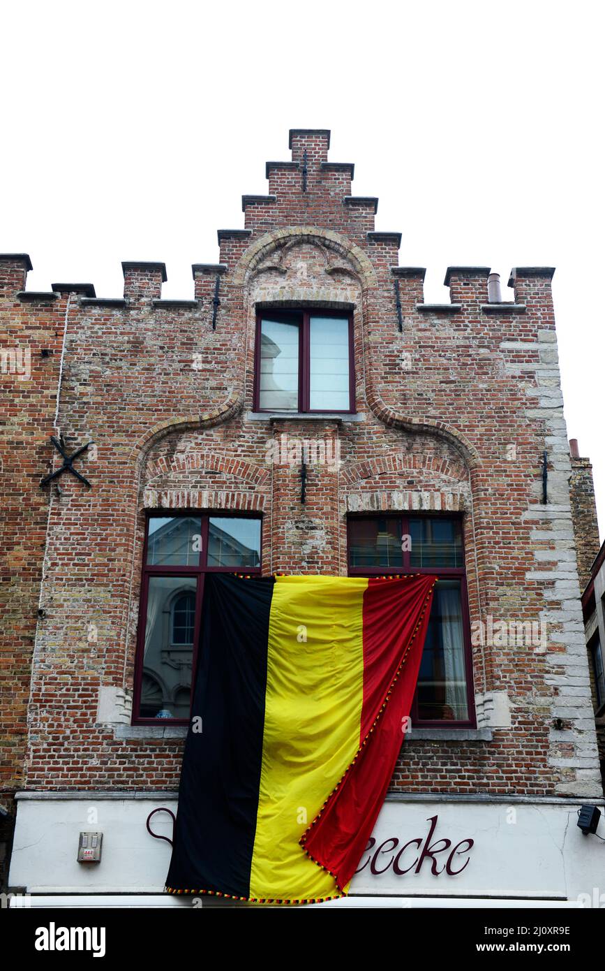 Die belgische Flagge hing an einem alten Gebäude für die Feierlichkeiten zum Nationalfeiertag in Brügge, Belgien. Stockfoto