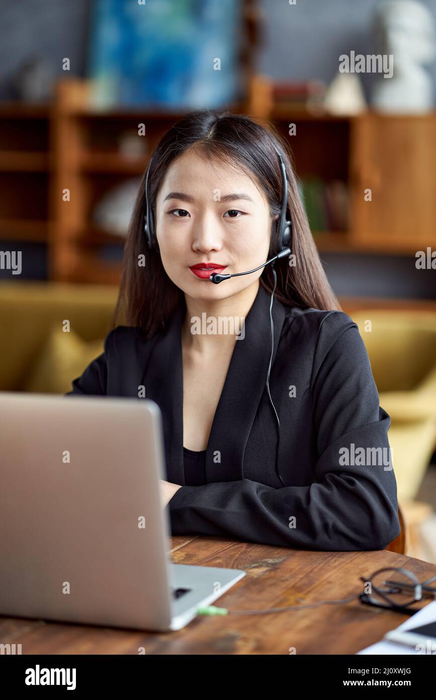 Glückliche asiatische Geschäftsfrau im Headset sprechen durch Konferenzgespräch und Video-Chat Stockfoto