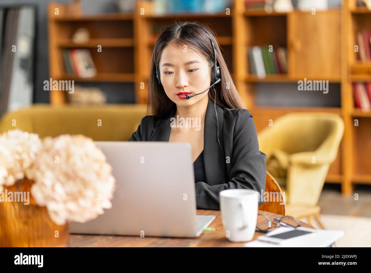 Asiatische Geschäftsfrau im Headset spricht per Konferenzgespräch und Video Chatten Stockfoto