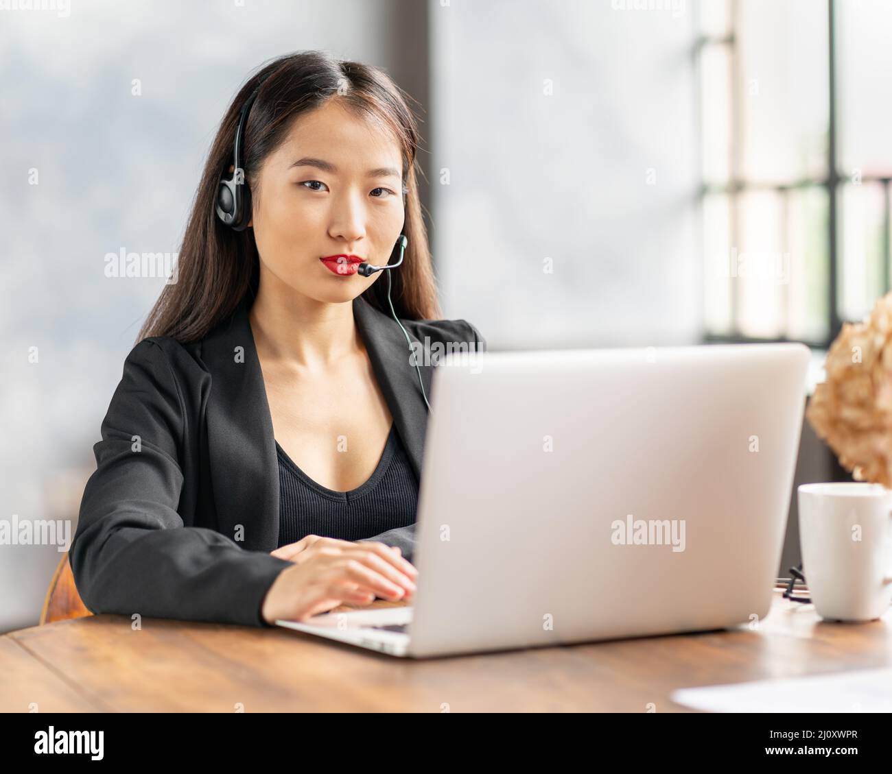 Glückliche asiatische Geschäftsfrau im Headset sprechen durch Konferenzgespräch und Video-Chat Stockfoto