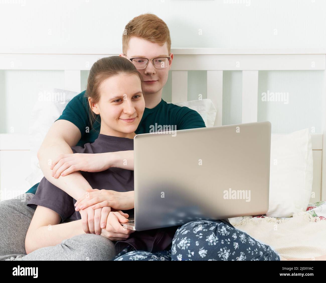 Teenager in der Liebe liegen auf dem Bett, sehen Filme auf Laptop während der Quarantäne wegen Coronavirus Pandemie Stockfoto