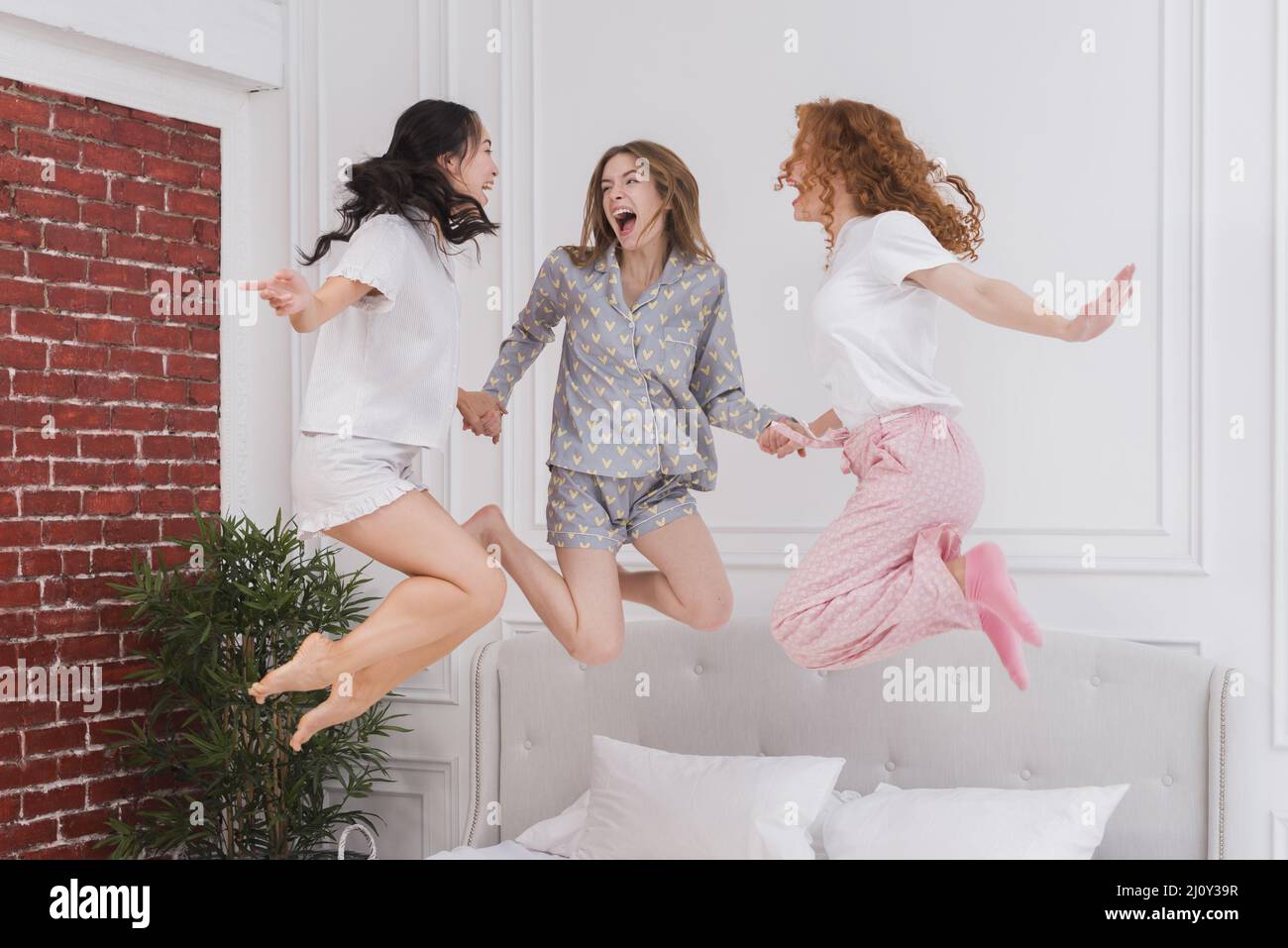 Junge Freundinnen springen ins Bett. Hochwertige Fotos Stockfoto