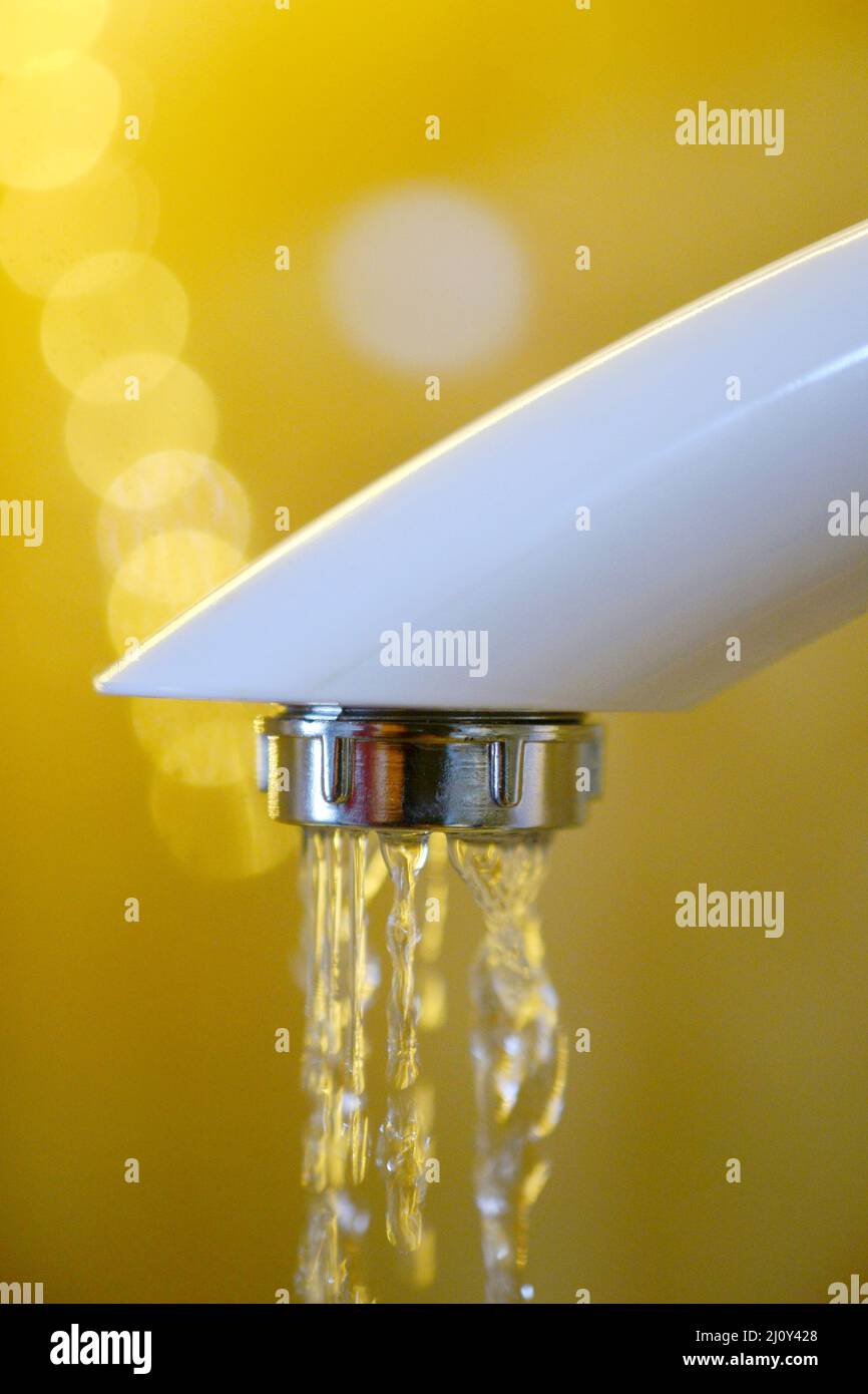 Das Wasser läuft aus einem weißen Plastikwasserhahn. Nahaufnahme Stockfoto